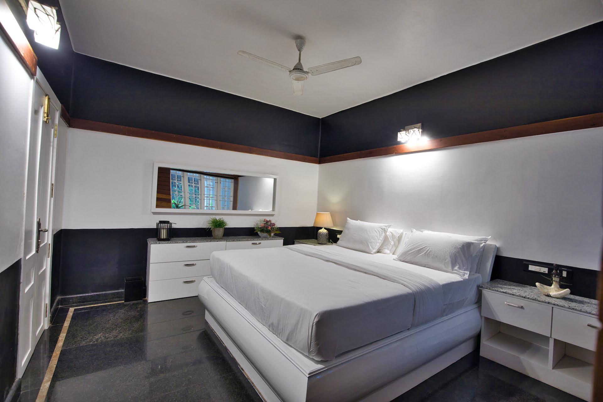 Bedroom in the Executive Suite at Softouch Ayurveda Village, Kerala, featuring a black and white themed decor, providing a modern and stylish ambiance