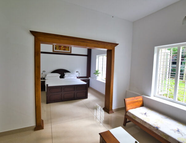 Bedroom view of the Grand Villa at Softouch Ayurveda Village, Kerala, featuring an attached living room, providing a spacious and comfortable stay