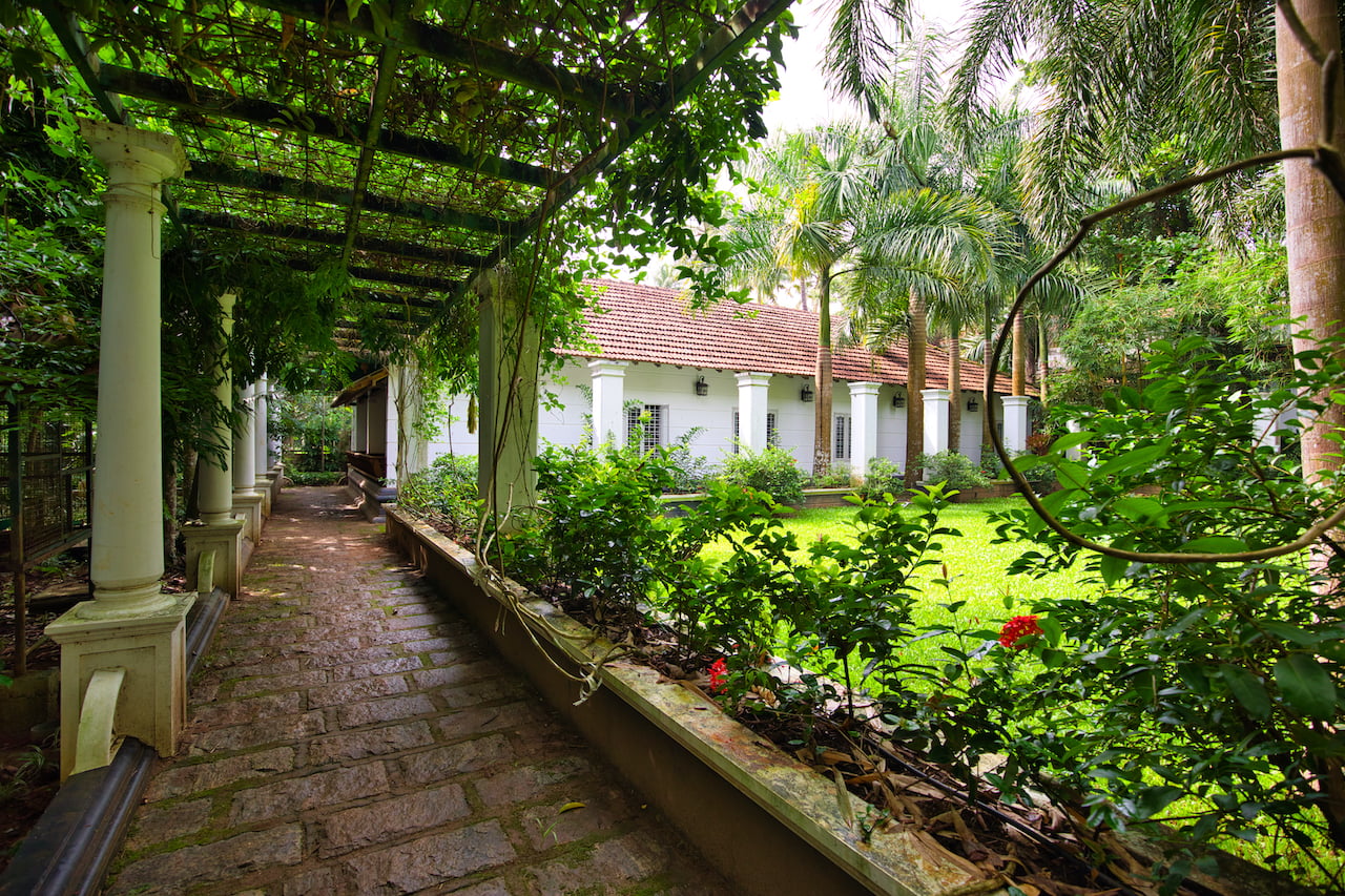 Exterior view of the Grand Villa at Softouch Ayurveda Village, Kerala, showcasing lush green lawns, privacy, and a scenic walkway, offering a serene and spacious retreat