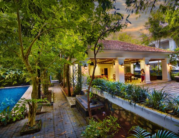 A luxurious pool villa at Softouch Ayurveda Village in Kerala, featuring a private swimming pool surrounded by lush gardens, comfortable outdoor seating, and a serene ambiance.